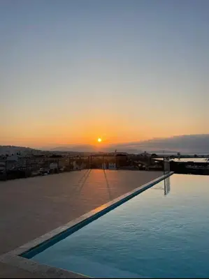a sunset over a swimming pool on top of a building at Piscine Rooftop Résidence Neuve in Saint-Laurent-du-Var
