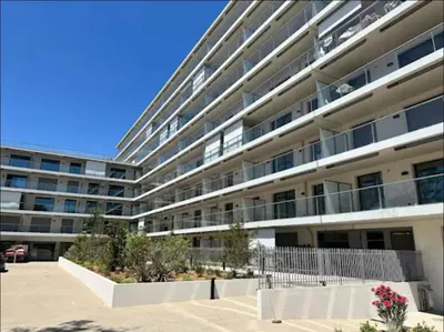 a large apartment building with a parking lot at Piscine Rooftop Résidence Neuve in Saint-Laurent-du-Var