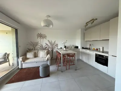 a kitchen and living room with a couch and a table at Piscine Rooftop Résidence Neuve in Saint-Laurent-du-Var