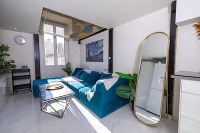 a living room with a blue couch and a mirror at Duplex suite 50m de la plage Carré d'Or Nice in Nice