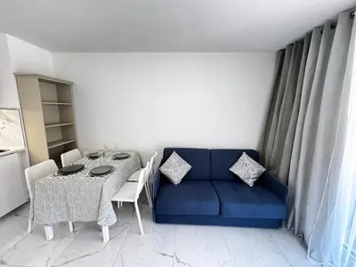 a living room with a blue couch and a table at Luxueux appartement climatisé avec piscine & parking in Saint-Laurent-du-Var