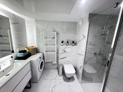 a bathroom with a washing machine and a shower at Luxueux appartement climatisé avec piscine & parking in Saint-Laurent-du-Var