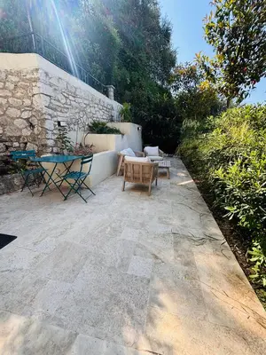 a patio with a table and chairs and a stone wall at Appartement 1 chambre - grande terrasse in Nice