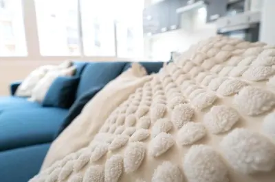 a white blanket sitting on a blue couch at Grand appartement idéal famille, proche plage, bon emplacement pour visiter la Côte d'Azur in Nice