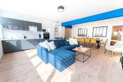a living room with a blue couch and a kitchen at Grand appartement idéal famille, proche plage, bon emplacement pour visiter la Côte d'Azur in Nice