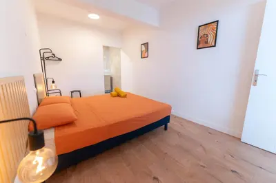 a bedroom with a bed with orange sheets and a lamp at Grand appartement idéal famille, proche plage, bon emplacement pour visiter la Côte d'Azur in Nice