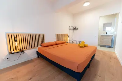 a bedroom with a bed with orange sheets and a window at Grand appartement idéal famille, proche plage, bon emplacement pour visiter la Côte d'Azur in Nice