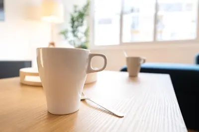 a white coffee cup sitting on top of a table at Grand appartement idéal famille, proche plage, bon emplacement pour visiter la Côte d'Azur in Nice