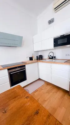 a kitchen with white cabinets and a wooden floor at L'appart in Nice