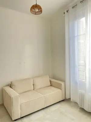 a white couch in a white room with a window at Havre de Paix à Nice in Nice