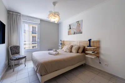 a bedroom with a large bed and a window at FEEL HOME - CAIS De PIERLAS in Nice