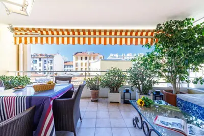 a balcony with tables and chairs and a view of a city at FEEL HOME - CAIS De PIERLAS in Nice