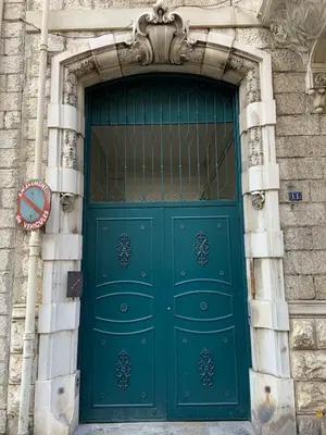 a green door in a stone building with a clock at Magnifique studio Centre-ville in Nice