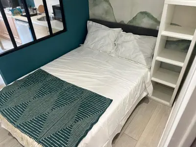 a bedroom with a bed with white sheets and shelves at Studio du Domaine du Piol in Nice