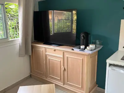 a television on top of a wooden cabinet in a kitchen at Studio du Domaine du Piol in Nice