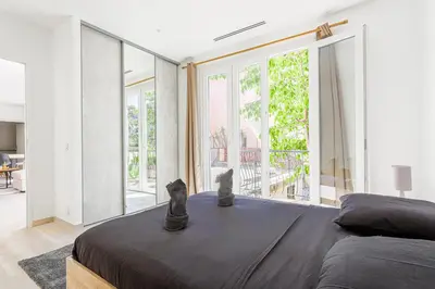 a bedroom with a large bed with two cats sitting on it at Sàvega - Climatisé et Proche Plage in Nice