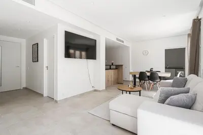 a living room with a white couch and a tv at Sàvega - Climatisé et Proche Plage in Nice