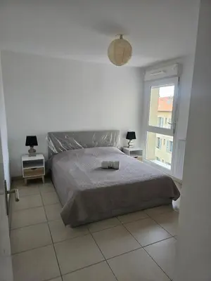 a white bedroom with a bed and a window at Résidence le vernier in Nice