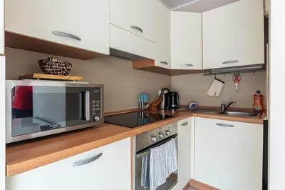 a kitchen with white cabinets and a microwave at Studio cœur de ville et au calme in Cagnes-sur-Mer