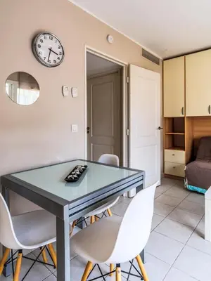 a dining room table with chairs and a clock on the wall at Studio cœur de ville et au calme in Cagnes-sur-Mer