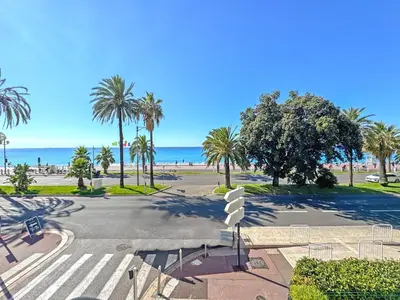 an empty street with palm trees and the beach at Belle Epoque Azur Promenade Nice in Nice