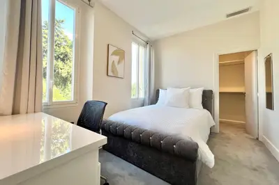 a bedroom with a bed and a desk and a window at Villa La Mascotte in Beaulieu-sur-Mer