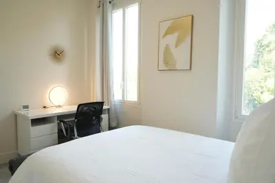 a bedroom with a bed and a desk and a window at Villa La Mascotte in Beaulieu-sur-Mer