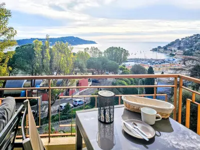 a table on a balcony with a view of the water at Beau 2 pieces avec vue imprenable sur la rade in Villefranche-sur-Mer
