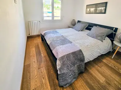 a bedroom with a large bed with a wooden floor at Beau 2 pieces avec vue imprenable sur la rade in Villefranche-sur-Mer