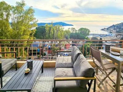 a patio with a couch and a table on a balcony at Beau 2 pieces avec vue imprenable sur la rade in Villefranche-sur-Mer