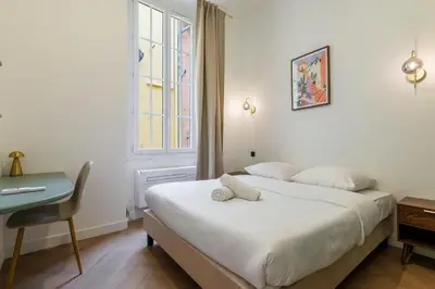 a bedroom with a bed and a desk and a window at Charme et modernite au coeur du Vieux Nice in Nice