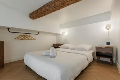 two beds in a room with white walls and wood floors at Charme et modernite au coeur du Vieux Nice in Nice