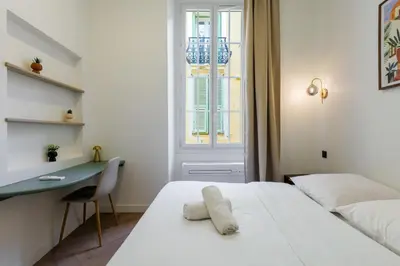 a bedroom with a bed and a desk and a window at Charme et modernite au coeur du Vieux Nice in Nice