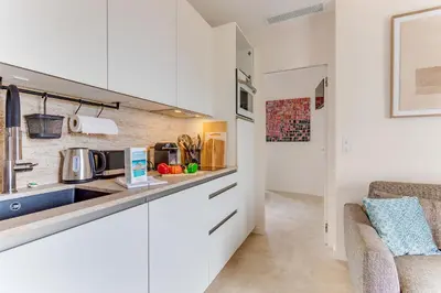 a kitchen with white cabinets and a sink at COCO BEACH AP4476 by Riviera Holiday Homes in Nice