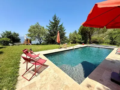 a pool with a red umbrella and chairs and a red umbrella at Havre de paix proche de Nice in Aspremont