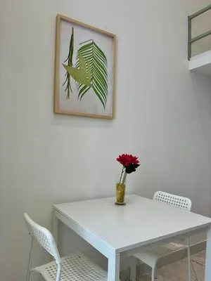 a white dining room table with a vase of flowers at Studio Dore Fshh in Nice