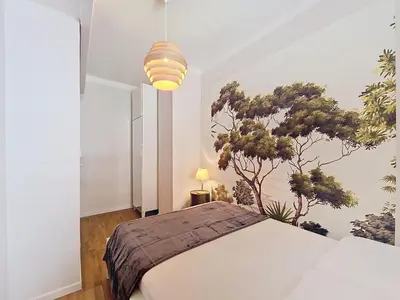 a bedroom with a bed and a tree mural on the wall at Nestor&Jeeves - PROMENADE DU SUD - Vue Mer in Nice