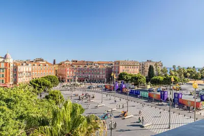 a city with a street with people and a train at Exceptional location, 2BR right on Place Massena, Newly Renovated in Nice