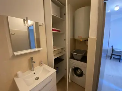 a bathroom with a sink and a washing machine at Nice hillside with 100 sqm private garden in Nice