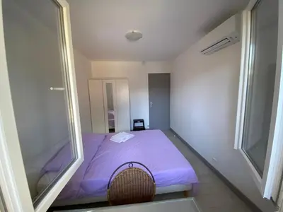 a small bedroom with a purple bed and a window at Nice hillside with 100 sqm private garden in Nice