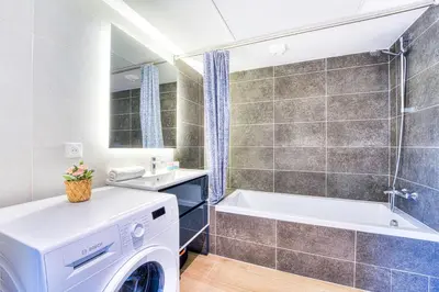 a bathroom with a washing machine and a tub at Appartement Fleuri vue mer - Welkeys in Saint-Laurent-du-Var