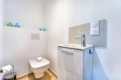 a white bathroom with a toilet and a sink at Appartement Fleuri vue mer - Welkeys in Saint-Laurent-du-Var