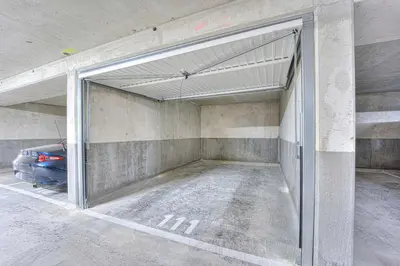an open garage with a car parked in it at Appartement Fleuri vue mer - Welkeys in Saint-Laurent-du-Var