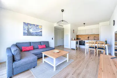 a living room and kitchen with a couch and a table at Appartement Fleuri vue mer - Welkeys in Saint-Laurent-du-Var