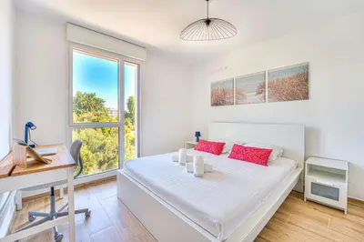 a bedroom with a bed and a desk and a window at Appartement Fleuri vue mer - Welkeys in Saint-Laurent-du-Var