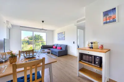 a living room with a table and a dining room at Appartement Fleuri vue mer - Welkeys in Saint-Laurent-du-Var