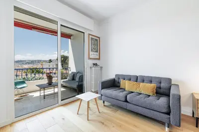 a living room with a couch and a balcony at Quiet & Open View - 1 Bdr Large Terrace in Nice