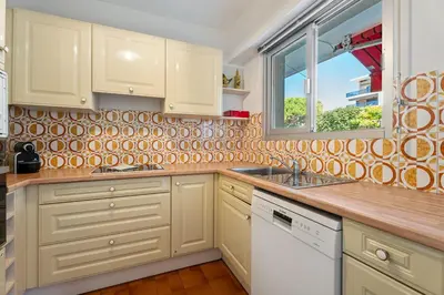 a kitchen with white cabinets and a window at Studio Mimosas - Welkeys in Cagnes-sur-Mer