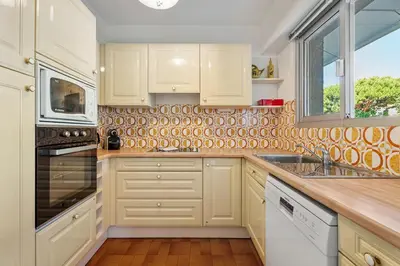 a kitchen with white cabinets and a sink and a window at Studio Mimosas - Welkeys in Cagnes-sur-Mer