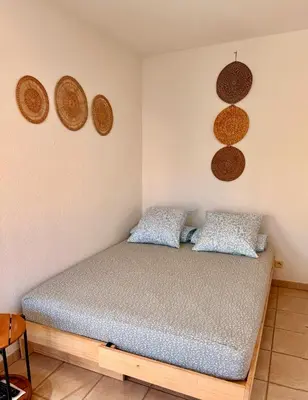 a bedroom with a bed and some baskets on the wall at Studio près mer et aéroport - Studio near sea and airport in Nice